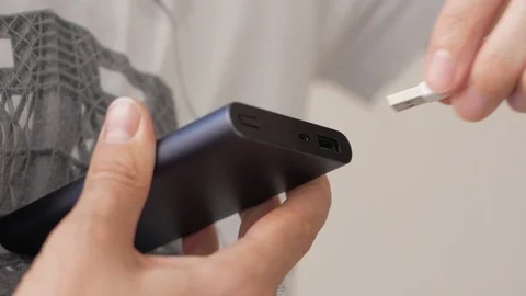 Male hand inserts cable from portable charging Stock Footage 99569625