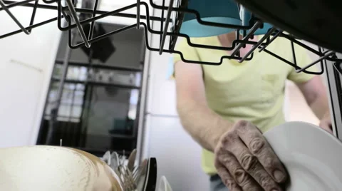Male hand loading plates into dishwasher in domestic kitchen Stock Footage