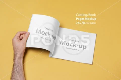 Male hand opened a catalog on yellow backdrop mock-up series PSD Template