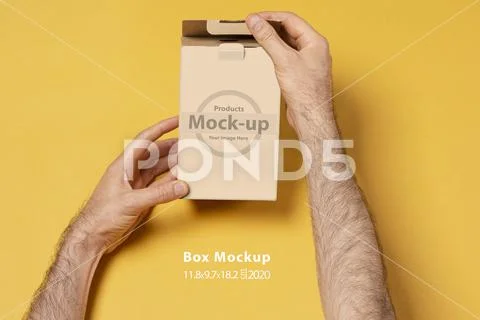 Male hand opening a small gift box in front of yellow background mock-up seri PSD Template
