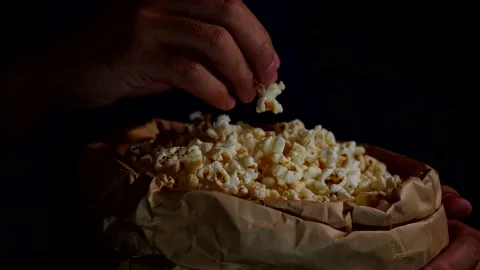 Male hand-picking popcorn from paper bucket closeup. Eating pop corn at cinema Stock Footage 143753123