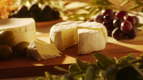 Male hand picking up a slice of camembert cheese from a rustic wooden board Stock Footage 334277105