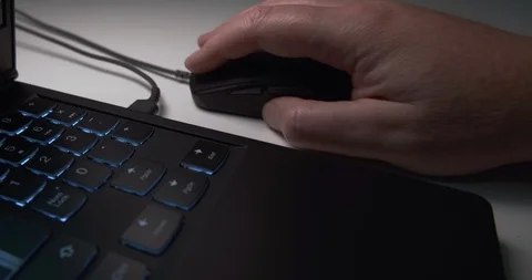 Male hand playing games with mouse on a laptop PC with blue backlit keyboard Stock Footage 118024159