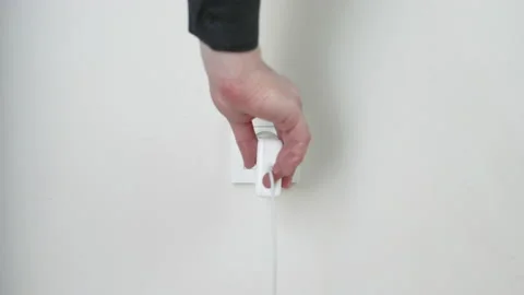 Male hand plugging and unplugging plug into white wall socket Stock Footage 231405329