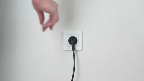Male hand plugging and unplugging plug into white wall socket Stock Footage 231405676
