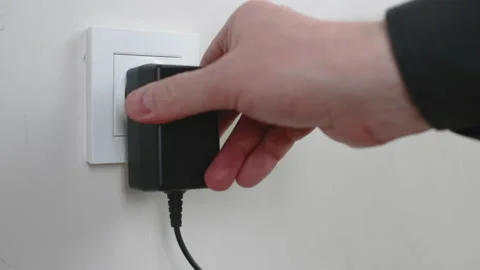 Male hand plugging and unplugging plug into white wall socket Stock Footage 231406305