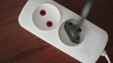 Male hand plugging black power plug into white multiple socket indoors Stock Footage 101337467