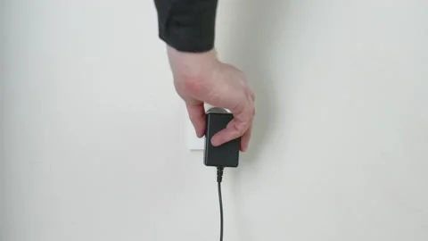 Male hand plugging unplugging charger cable plug into white wall power socket Stock Footage 232768871
