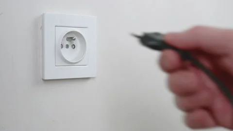 Male hand plugging unplugging charger cable plug into white wall power socket Stock Footage 232769875