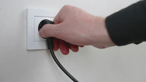 Male hand plugging unplugging charger cable plug into white wall power socket Stock Footage 232769917