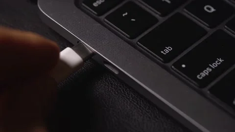 Male hand plugging in a white power USB-C or Type C Cable into a laptop computer Stock Footage 167964874