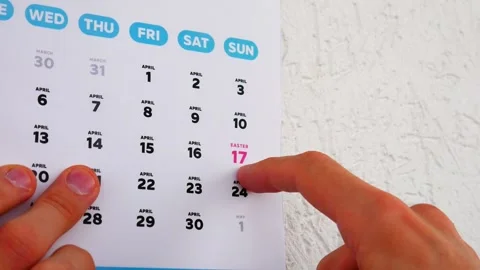 A male hand pointing finger to Easter date on the wall calendar April page 2022 Vidéo 175245737