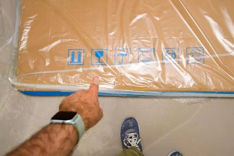 Male hand pointing to security elements icons on large cardboard box Foto stock