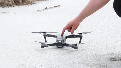 Male hand presses a button on a gray drone standing on the ground Video stock 134415940