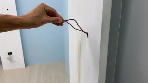 Male hand pulling electrical wire cable from wall. Interior painted blue Video stock 249730220