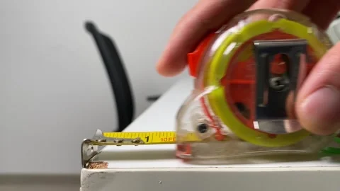 Male hand pulling roll of measuring tape on white table indoor office room Stock Footage 249375473