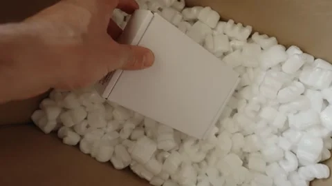 Male hand put box inside packaging foam peanuts or popcorn to be sent by mail Stock Footage 240485927