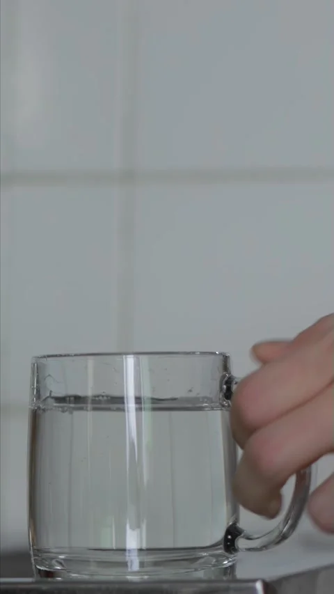 Male hand puts down clear mug with drinking water at home kitchen. Daily routine Stock Footage 328818885