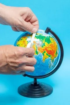 Male hand putting a patch on a globe. Geographical names on the globe in Russ Stock Photos