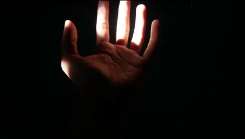 Male hand reaching for light in darkness on isolated black background. Stock Footage 304723210