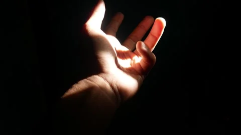 Male hand reaching for light in darkness on isolated black background. Stock Footage 304723221