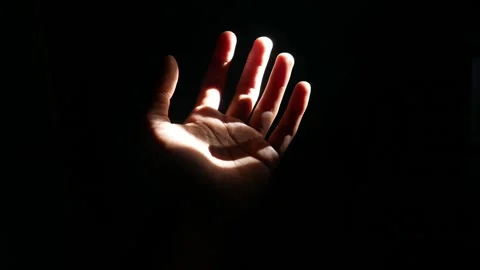 Male hand reaching for light in darkness on isolated black background. Stock Footage 304723225