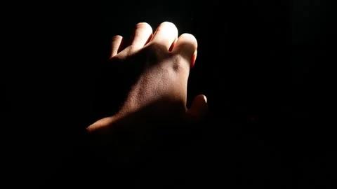 Male hand reaching for light in darkness on isolated black background. Stock Footage 304723227