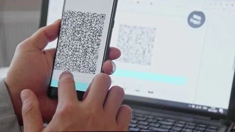 A male hand scans a QR code with a smartphone from a laptop monitor. A text file Stock Footage 171724066