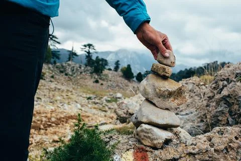 Male hand sets a pointer out of stones - Cairn 库存照片