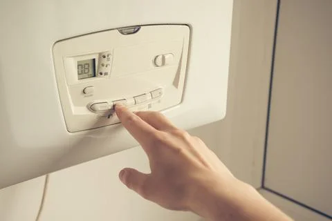 Male hand setting temperature on a heating boiler construction. Stock Photos