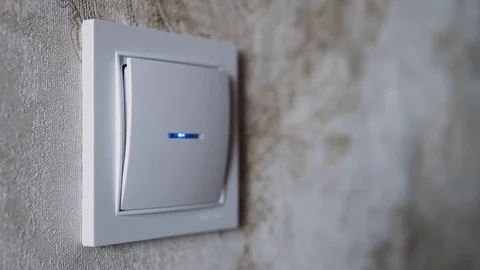 Male hand switch off and on a button on a light-grey wall Stock Footage 124440636
