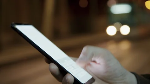 Male hand texting message on a cell phone at the night city on background Stock Footage 128033293