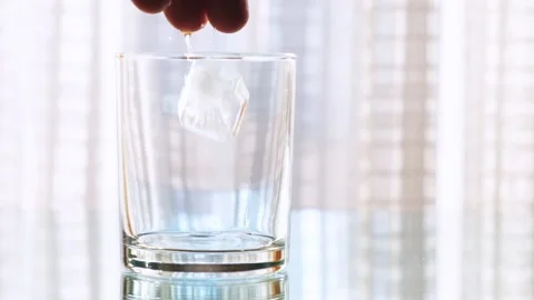 Male hand throws ice into an empty glass. Slow motion. Stock Footage 146013099