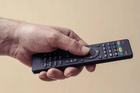 Male hand with a TV remote control close-up. The man turns on the TV Stock Photos