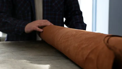 Male hand unrolling and touching leather roll. Rolls of industrial leather for Stock Footage