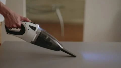 Male hand using handheld vacuum cleaner to remove dust and crumbs from kitchen Stock Footage 311564553