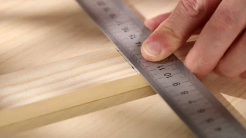 A male hand using a pencil to draw a straight line onto wood using a ruler. Stock Footage 245412493