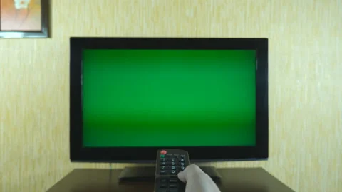 Male hand using a remote control to flipping channels on green screen TV. Arm of Stock Footage 87988202