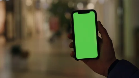 Male hand using smartphone with blank green screen in the street on walking Vídeo Stock 106333092