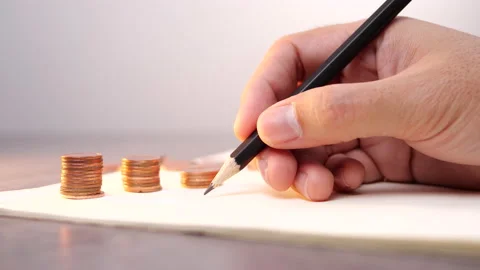 A male hand writing on a notebook with stack of coin for business and financial. Stock Footage 136749292