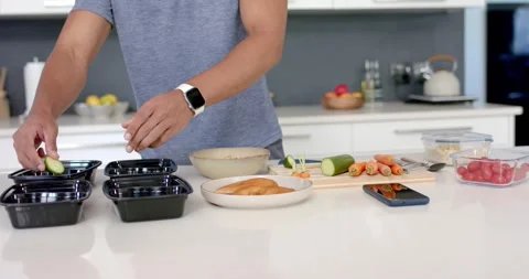 Male hands are starting slicing cucumber, carrots on counter, filling four meal Stock Footage 336437853