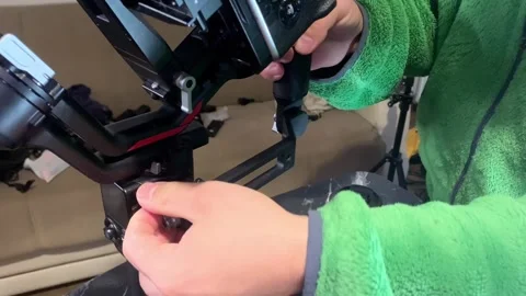 Male hands attaching handle to camera stabilizer close-up, tightening grip and Stock Footage 333478858