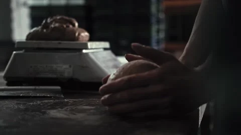 Male hands of baker shaping dough on floured wooden table. Process of bread and Stock Footage 344844390