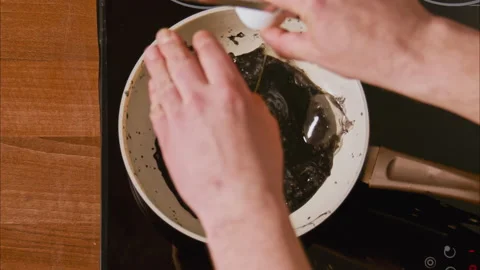 Male hands break an egg into a frying pan in black oil. top shot 100fps Video stock 196409727