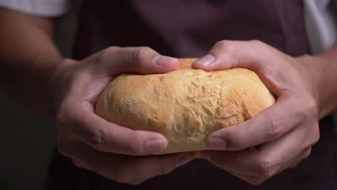 Male hands breaking fresh bread in slow motion Stockbeeldmateriaal 132679477