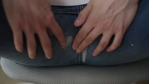 Male hands checking torn denim jeans at back seam while sitting on chair Stock Footage 318470629