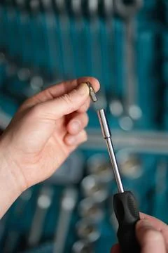 Male hands in close-up while attaching the removable tip to the screwdriver. Stock Photos