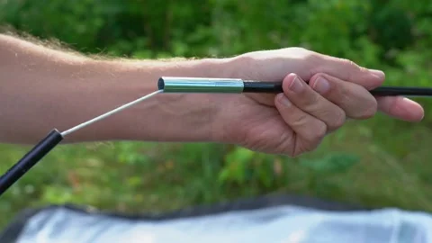 Male hands connecting elements of skeleton frame of camping tent together Stock Footage 144276625