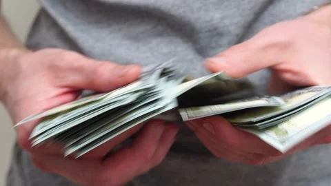 Male hands counting a stack of hundred-dollar US banknotes. Concept of Stock Footage 242484828
