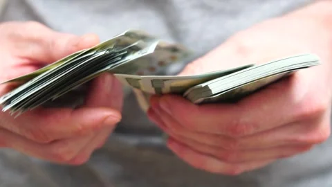Male hands counting a stack of hundred-dollar US banknotes. Concept of Stock Footage 244115625